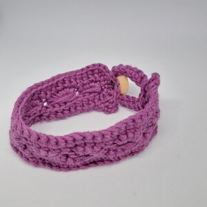 Può includere: Un braccialetto all'uncinetto viola con chiusura a perlina di legno.