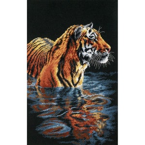 May include: A tiger with orange and black stripes swims in a dark blue body of water. The tiger's head is turned to the right, and its whiskers are visible. The water is rippling around the tiger.