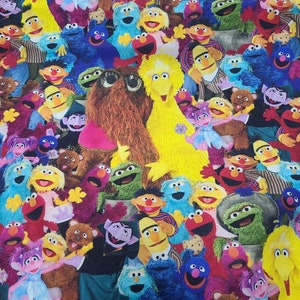 May include: A colourful fabric featuring a variety of Sesame Street characters, including Big Bird, Elmo, Cookie Monster, and Oscar the Grouch. The characters are arranged in a chaotic and playful pattern, creating a vibrant and fun design.