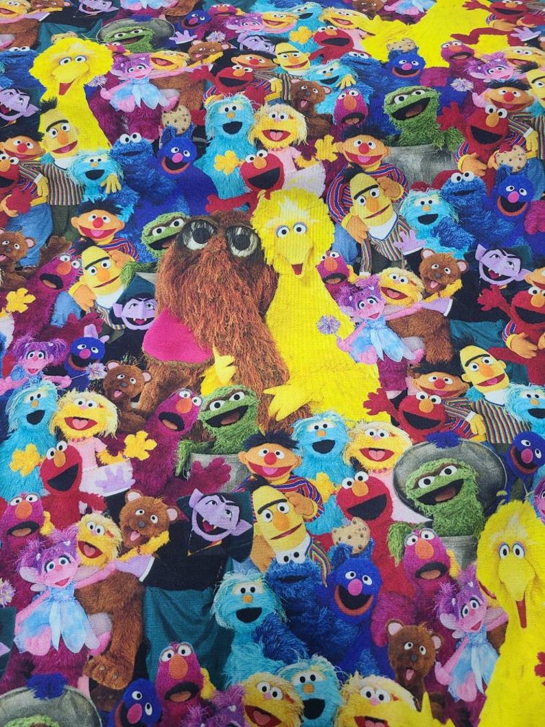May include: A colourful fabric featuring a variety of Sesame Street characters, including Big Bird, Elmo, Cookie Monster, and Oscar the Grouch. The characters are arranged in a chaotic and playful pattern, creating a vibrant and fun design.