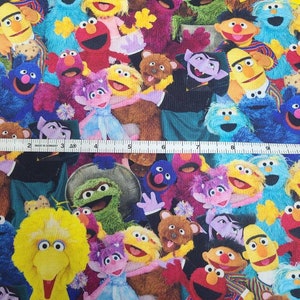 May include: A colourful fabric featuring a variety of Sesame Street characters, including Big Bird, Elmo, Cookie Monster, and Oscar the Grouch. The fabric is perfect for crafting projects, such as quilts, pillows, and tote bags.