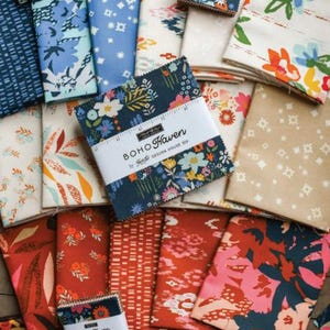 May include: A collection of fabric squares in various floral and geometric patterns. The color palette includes blues, reds, oranges, and tans. Several bundles are labeled "Boho Haven" by Figtree Design House. The fabrics are likely for quilting or crafting.