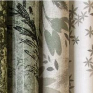 May include: A collection of rolled fabric bolts featuring various botanical and geometric patterns. The color palette includes shades of green, gray, and white. Designs range from floral and leaf motifs to abstract shapes, suitable for crafting or home decor projects.