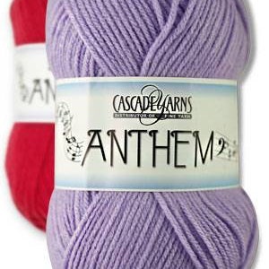 May include: Two skeins of yarn, one red and one lavender. The lavender skein is in focus, with a label that reads "CASCADE YARNS ANTHEM". The yarn is tightly wound, suggesting it is for knitting or crochet projects.