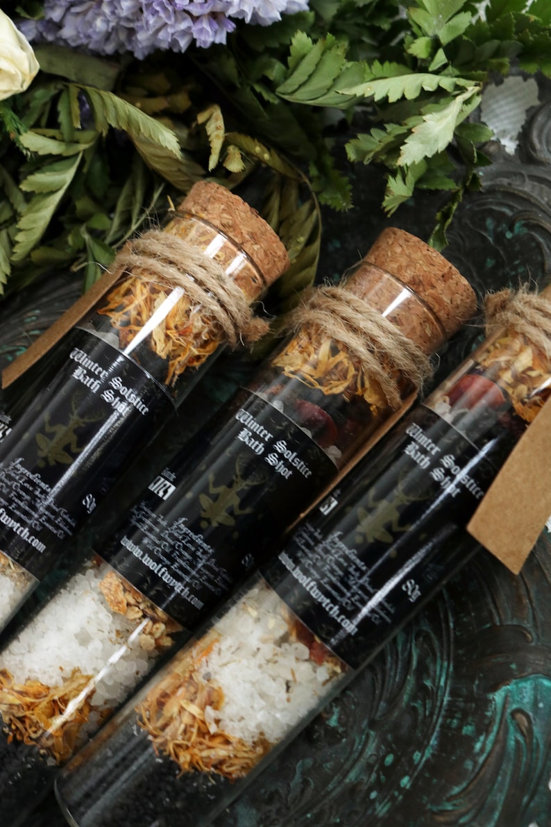 May include: Three glass test tubes filled with bath salts and dried herbs, labeled "Winter Solstice Bath Shot". The tubes are tied with twine and have cork stoppers.