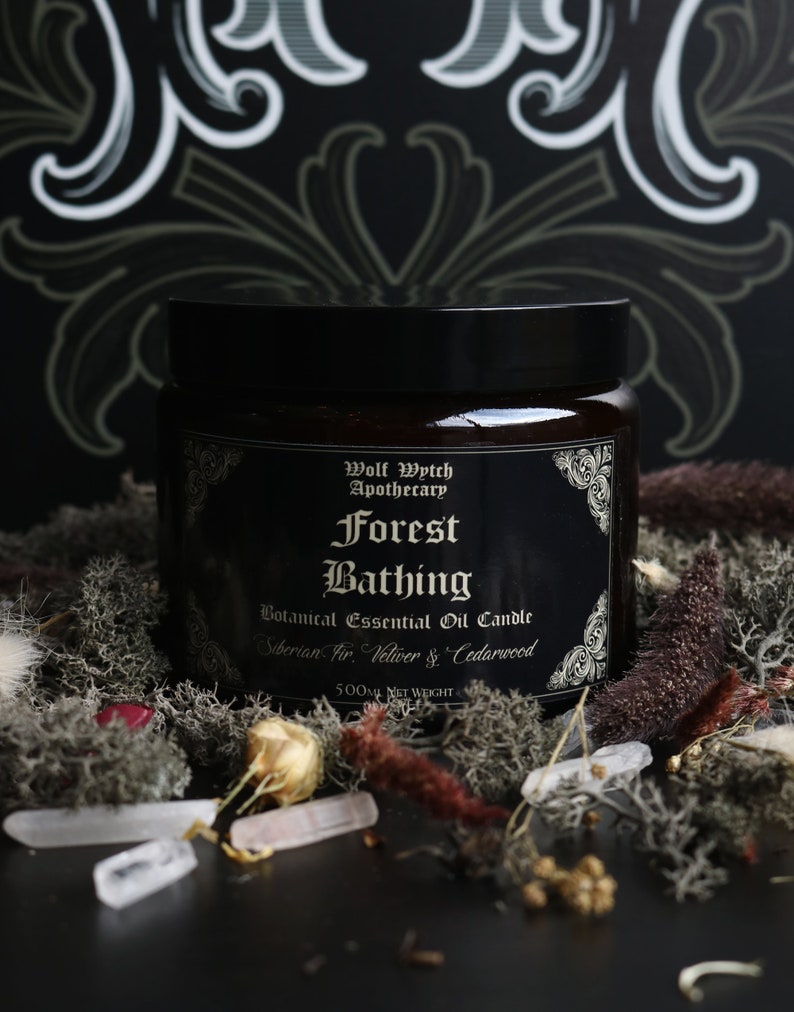 K&ouml;nnte beinhalten: Eine schwarze Glaskerze mit einem goldenen Etikett, auf dem "Wolf Wytch Apothecary Forest Bathing Botanical Essential Oil Candle Siberian Fir, Vetiver & Cedarwood 500ml Net Weight" steht.