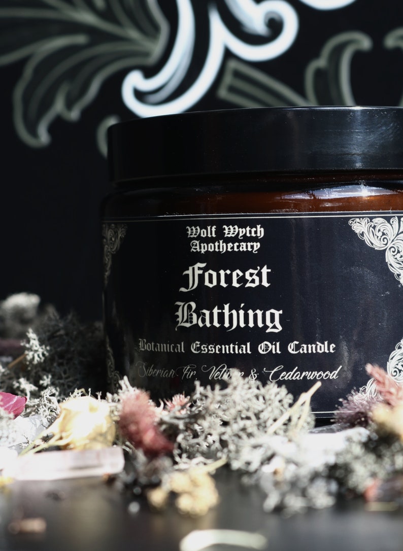 K&ouml;nnte beinhalten: Ein schwarzes Kerzengef&auml;&szlig; mit einem wei&szlig;en Etikett, auf dem "Wolf Wytch Apothecary Forest Bathing Botanical Essential Oil Candle Siberian Fir, Vetiver & Cedarwood" steht.