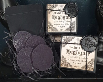 May include: A black box with a black wax seal and the text "Morbid Love Highgate Suede Tonka & Amber Coconut Wax Melts 65g" on the front. The box contains four black wax melts with a decorative design.