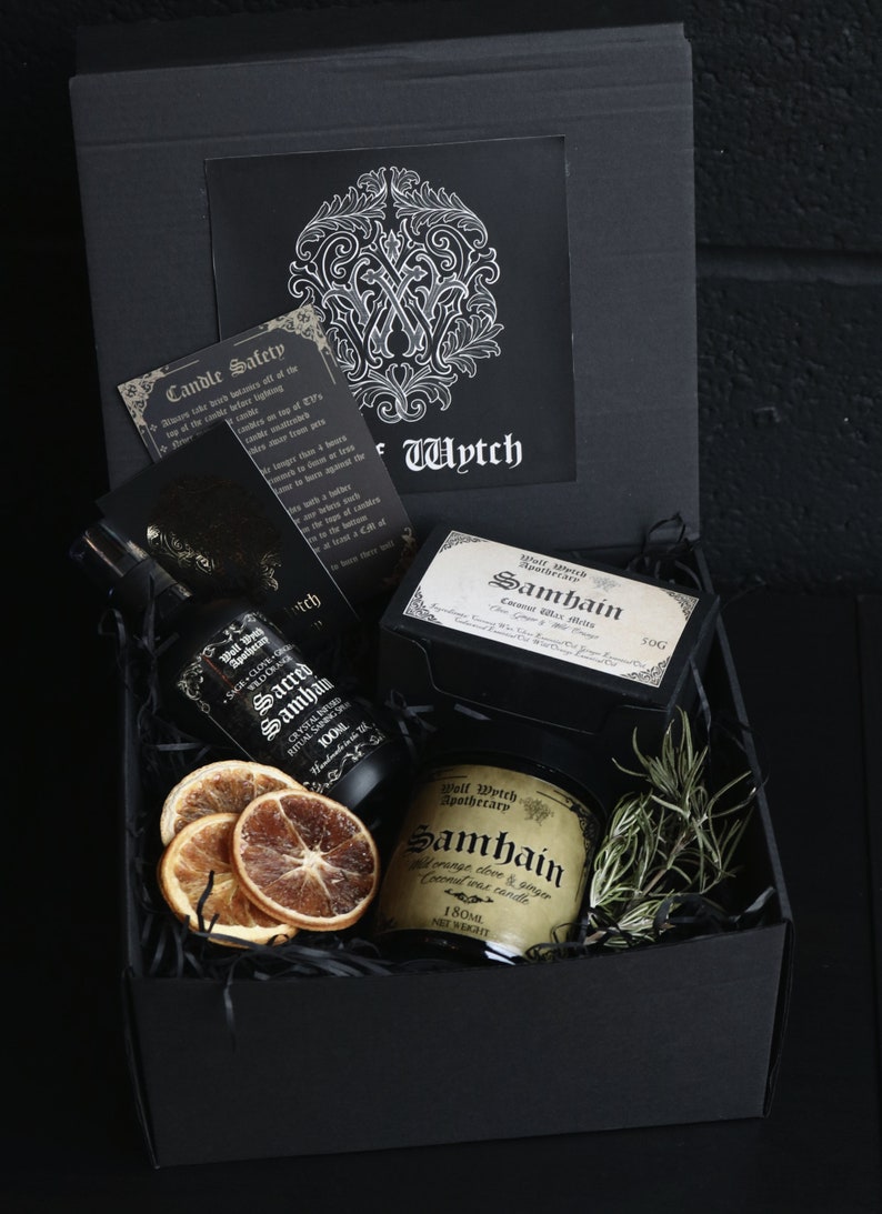 May include: A black gift box filled with a black and gold candle, a bottle of essential oil, and a bag of wax melts. The candle and oil are labeled "Samhain" and the wax melts are labeled "Samhain Coconut Wax Melts".