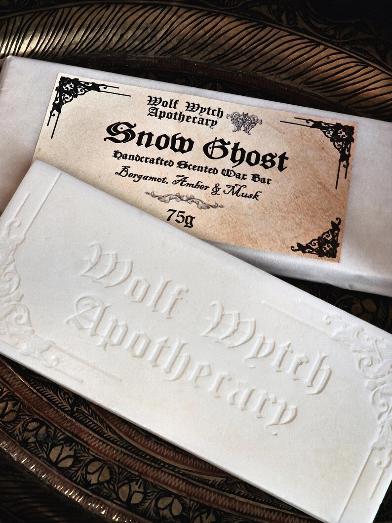 K&ouml;nnte beinhalten: Eine wei&szlig;e Seife mit dem gepr&auml;gten Text "Wolf Wytch Apothecary" und einem Etikett mit der Aufschrift "Snow Ghost" mit Duftdetails. Die Seife wiegt 75g.