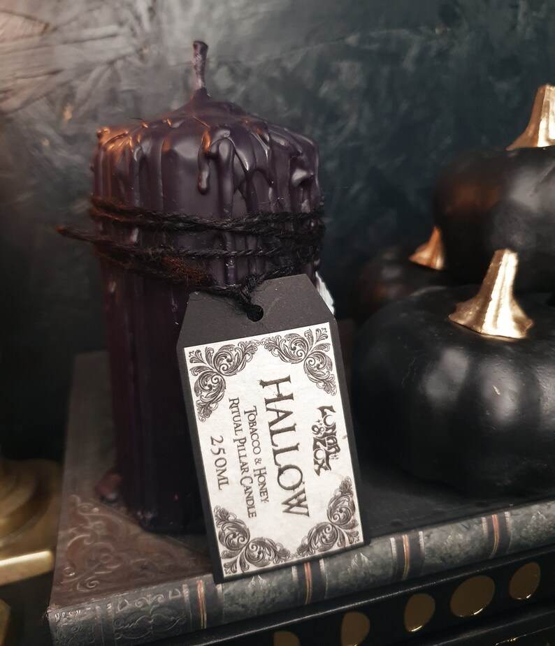 May include: Black pillar candle with a dripping wax design, tied with twine and labelled "HALLOW Tobacco & Honey Ritual Pillar Candle 2.5 oz"