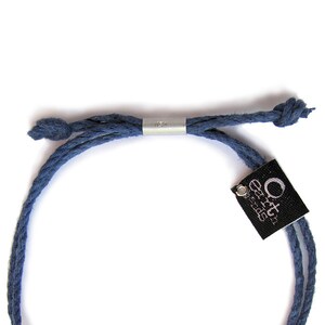 May include: A blue cotton cord bracelet with a silver adjustable slider and a black tag that reads "Orca Designs".