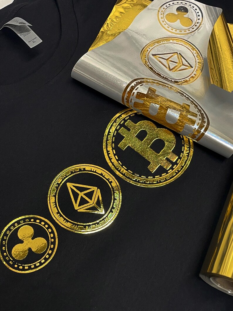 May include: A black t-shirt with gold foil iron-on designs of cryptocurrency logos. The logos include Bitcoin, Ethereum, and Ripple.