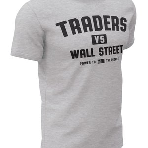 May include: Gray t-shirt with black text that reads "TRADERS VS WALL STREET POWER TO THE PEOPLE" with an American flag graphic.