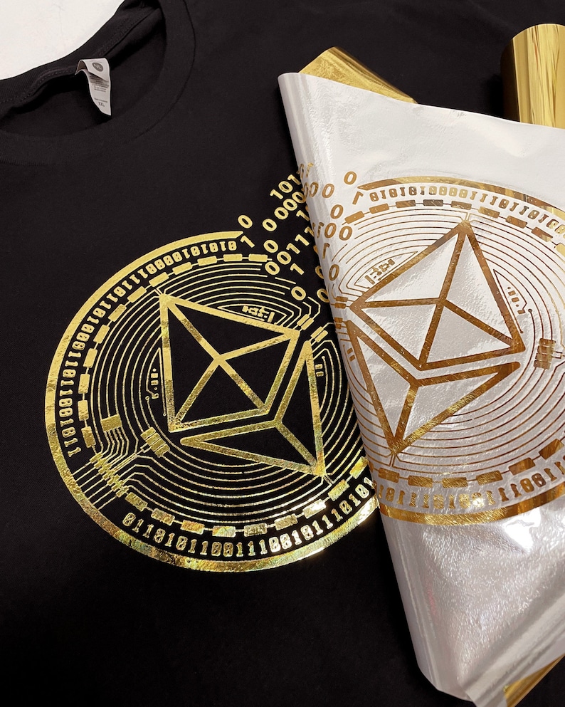 May include: A black t-shirt with a gold foil design of a geometric shape surrounded by a circle of binary code.
