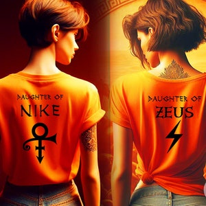 May include: Two women wearing orange t-shirts with different Greek god designs. The woman on the left has a Nike symbol and the text "Daughter of Nike". The woman on the right has a lightning bolt symbol and the text "Daughter of Zeus".