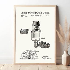 Puede incluir: Ilustración de patente enmarcada de un micrófono, fechada el 5 de abril de 1938, con el texto "United States Patent Office". El dibujo en blanco y negro incluye diagramas detallados de los componentes del micrófono y un gráfico de globo.
