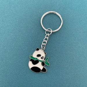 May include: A silver key chain with a black and white panda charm holding a green bamboo shoot.