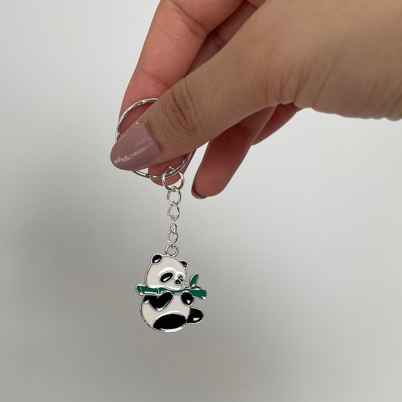 May include: A silver keychain with a black and white panda charm holding a green bamboo shoot.