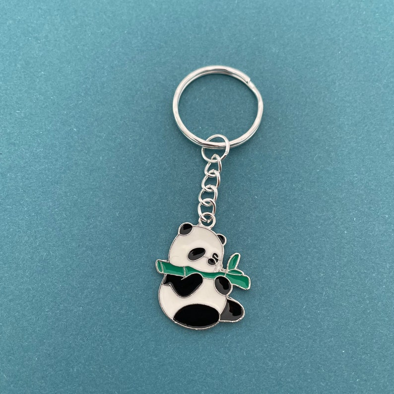 May include: A silver keychain with a black and white panda bear charm holding a green bamboo shoot.
