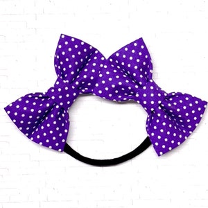 May include: Purple headband with a white polka dot bow.