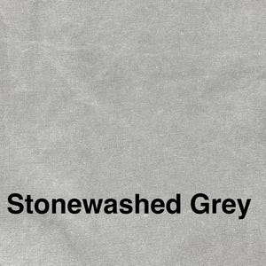 May include: Close-up of a textured, stonewashed grey fabric. The words "Stonewashed Grey" are printed in black, centered at the bottom of the image. The fabric has a subtle, mottled appearance.