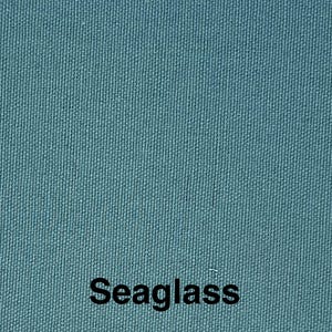 May include: Close-up of a textured fabric in a teal color. The word "Seaglass" is printed in black at the bottom of the image. The fabric has a woven appearance.