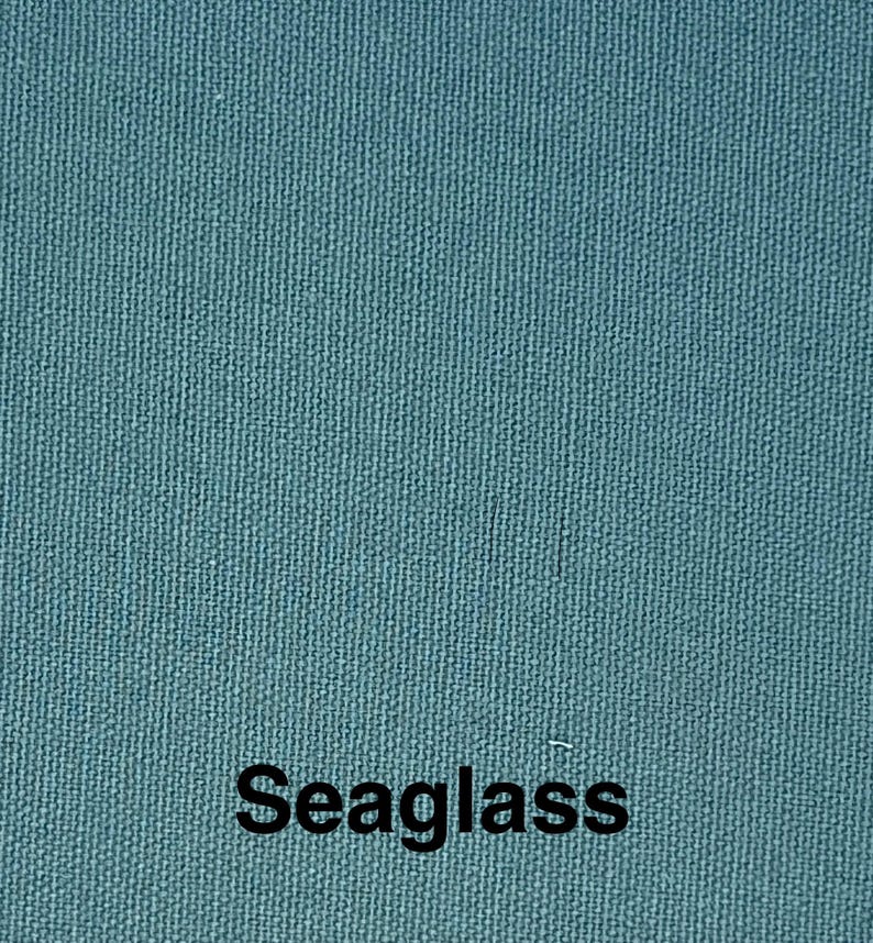 May include: Close-up of a textured fabric in a teal color. The word "Seaglass" is printed in black at the bottom of the image. The fabric has a woven appearance.