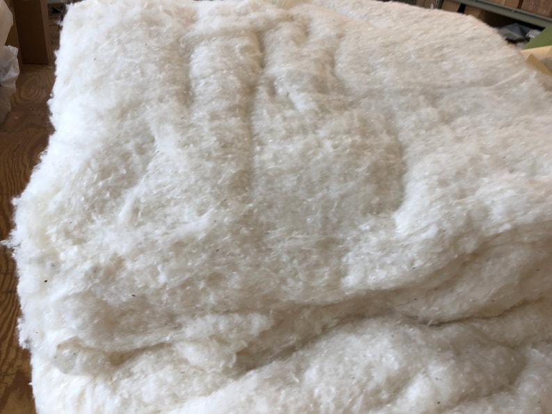 May include: A large pile of white cotton batting, a fluffy and soft material used for stuffing pillows, quilts, and other crafts.