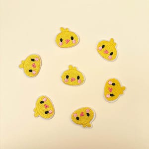 May include: Seven yellow chick patches with embroidered details. Each patch features a chick design with black eyes, pink cheeks, and a white border. These patches are suitable for clothing or craft projects.