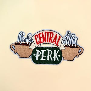 May include: Embroidered patch featuring the "Central Perk" logo from the TV show Friends. The design includes two brown coffee cups with steam, a red banner with "CENTRAL" and a green sign with "PERK" in white.
