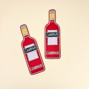 May include: Two red Campari bottle patches with white and black text. The patches have a white border and a yellow top. The word "Campari" is printed on the front of the bottle.