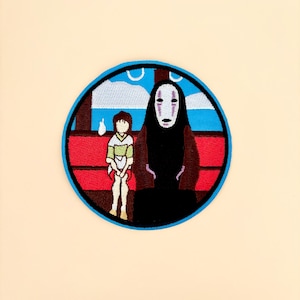 May include: Embroidered patch featuring characters from a Japanese animated film. The patch is circular with a blue border. It depicts a girl and a figure in a black robe and mask, set against a red and blue background, with white clouds.