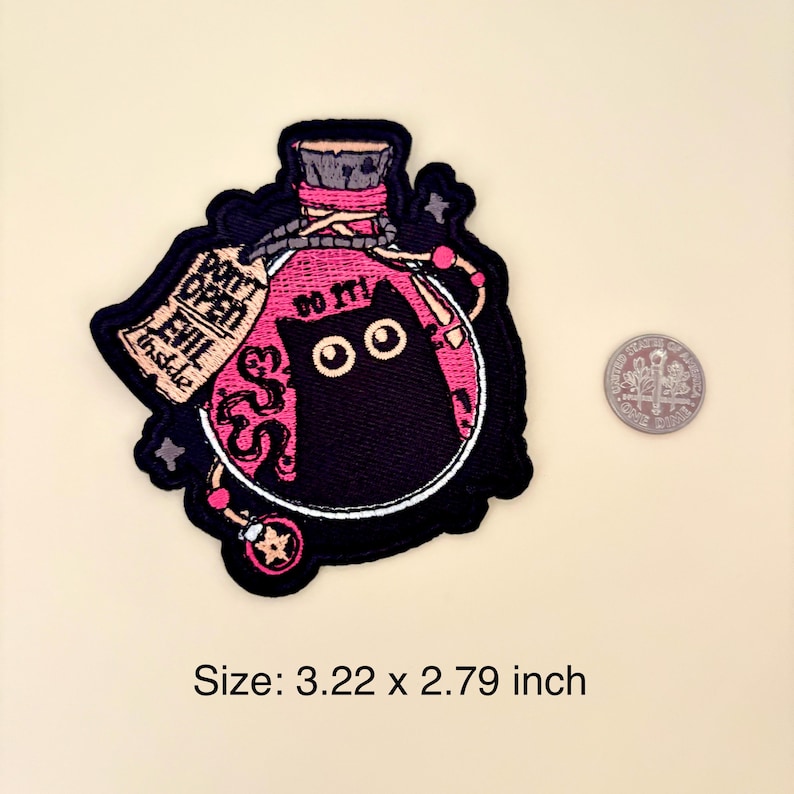 May include: Embroidered patch featuring a black cat inside a pink potion bottle. The patch includes the text "DON'T OPEN EVIL inside" and "DO IT!" The patch measures 3.22 x 2.79 inches.