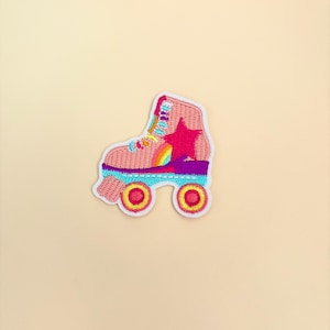May include: Pink roller skate with a rainbow and star design. The skate has white wheels with yellow centers.