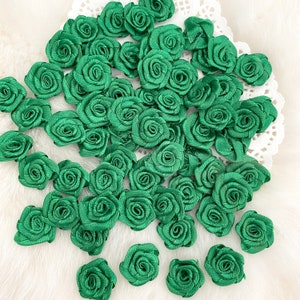 May include: A large quantity of green fabric rose embellishments. The roses are made of satin ribbon and are perfect for adding a touch of elegance to crafts and projects.