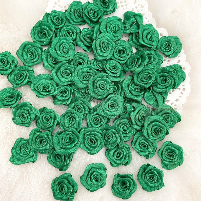 May include: A large quantity of green fabric rose embellishments. The roses are made of satin ribbon and are perfect for adding a touch of elegance to crafts and projects.