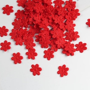 May include: A collection of small, vibrant red fabric flower embellishments scattered on a white surface. Each flower has a detailed, textured appearance, perfect for craft projects or adding a decorative touch.