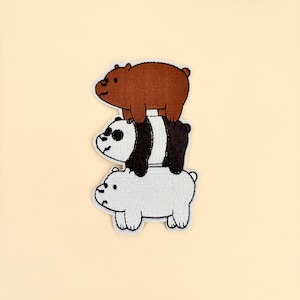 May include: Embroidered patch featuring three cartoon bears stacked on top of each other. The top bear is brown, the middle bear is black and white, and the bottom bear is white. The patch has a white border.