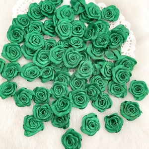 May include: A large collection of green fabric rosettes, arranged in a random pattern. The rosettes are made of a soft, silky fabric and have a delicate, ruffled texture.