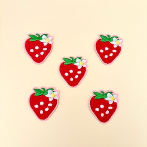 May include: Five red embroidered strawberry patches with white seeds and green leaves. Each strawberry has a white flower with a yellow center.