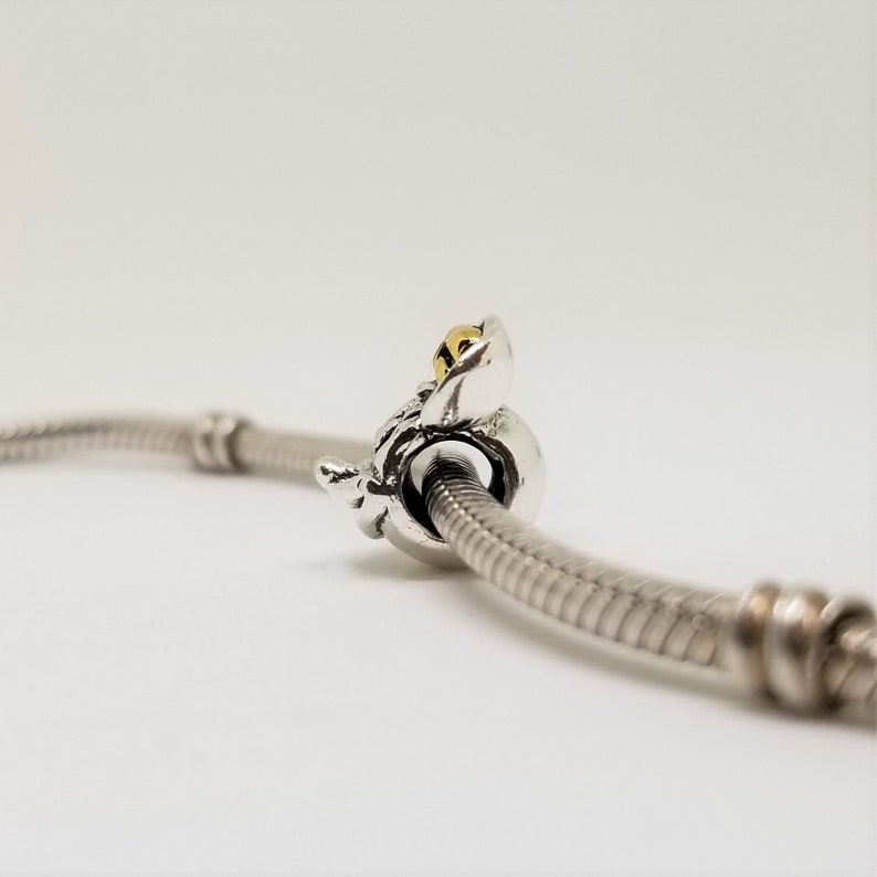May include: A silver charm bracelet with a silver and gold bee charm. The bee charm has a gold body and silver wings.
