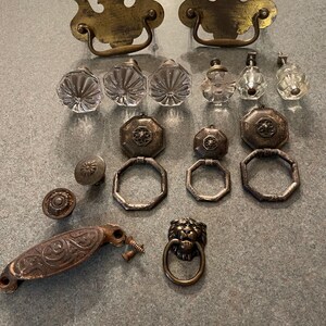 May include: A collection of vintage cabinet hardware, including brass drawer pulls, crystal knobs, and a lion head pull.
