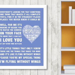 May include: A framed print with a white border, featuring lyrics in white text on a blue background. The text includes song lyrics and a heart-shaped design with the words "Flying Without Wings" and "Westlife."