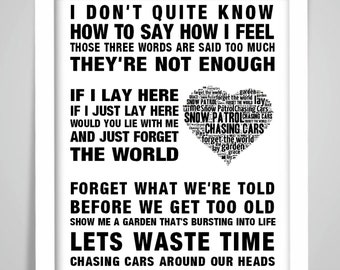 May include: Black and white typography print with a heart-shaped word cloud in the center. The text reads "I don't quite know how to say how I feel. Those three words are said too much. They're not enough. If I lay here. If I just lay here. Would you lie with me and just forget the world. Forget what we're told before we get too old. Show me a garden that's bursting into life. Let's waste time chasing cars around our heads."