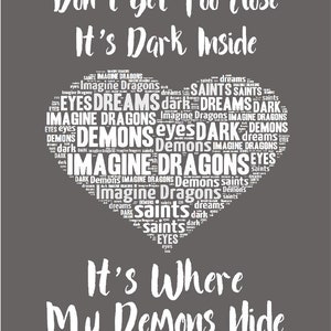 May include: A dark gray background with white text that reads "Don't Get Too Close It's Dark Inside" and a heart-shaped word cloud with the words "Imagine Dragons, Demons, Saints, Dreams, Dark, Eyes" in white. The text below the heart reads "It's Where My Demons Hide".