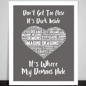 May include: A gray background with white text that reads "Don't Get Too Close It's Dark Inside" and a heart-shaped word cloud with the words "Imagine Dragons" and "Demons" repeated many times. The text below the heart reads "It's Where My Demons Hide".
