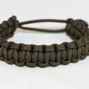 May include: A dark green paracord bracelet with a woven design.