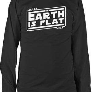 May include: Black long-sleeve shirt with a white graphic that reads "NASA THE EARTH IS FLAT LIES". The text is inside a white rectangle. The shirt is a crew neck.