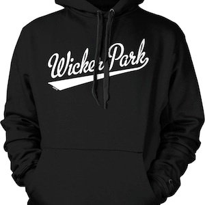 May include: A black hooded sweatshirt featuring a white graphic print on the chest that reads Wicker Park in a cursive script font, underlined by a white swoosh shape. The garment includes a front kangaroo pocket and matching black drawstrings.